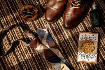 Wedding rings for bride and groom on smart phone near shoes for groom, leather belt, perfume bottle and tie in rustic style . Marriage concept