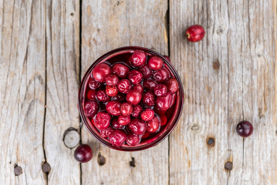 Wooden table with Cranberries (preserved) (detailed close-up shot; selective focus)
