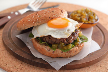 Hamburger with fried egg and gherkin salad