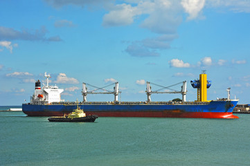 Tugboat assisting bulk cargo ship