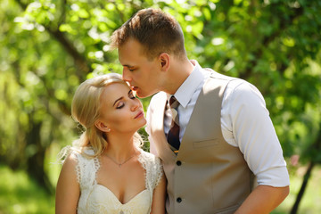 Wedding and marriage concept. Bride and groom kissing in fairytale park after wedding ceremony