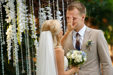 Wedding ceremony with emotions. Bride wipes away the tear of the groom face