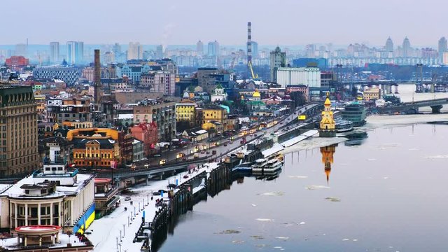 Kyiv, Ukraine. Aerial view of Podol and Dnipro river in the evening in Kyiv, Ukraine. Modern buildings and car traffic. Time-lapse at sunset, getting dark. Zoom in