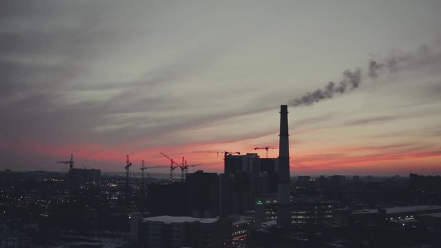 Time lapse of silhouettes of cranes works at urban sunset, toned