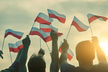 Fototapeta premium Poland patriots, back view. People raising polish flags up to the sky.