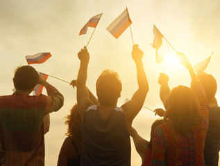 Peope with flags of Russia, back view. Patriotic family against sunset background. Glowing evening sunshine.