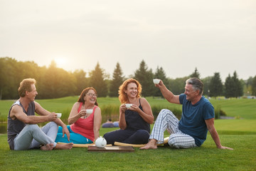 Fototapeta premium Group of senior friends chatting together in the park. Having fun outdoor in the summer. Tea party.