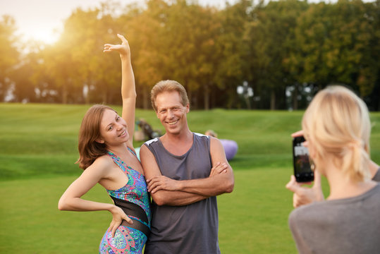 Happy couple making photo in the park. Man and woman posing for photo on smartphone outdoor.