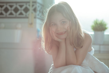 Fototapeta premium Portrait of pretty little child girl with white towel after shower in bright bathroom