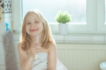 Portrait of pretty little child girl with white towel after shower  in bright bathroom