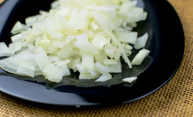 Finely chopped onions on a black plate.