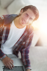 young man working on laptop and looking at camera. view from above