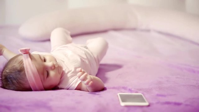 Cute girl playing with cellphone in bed.