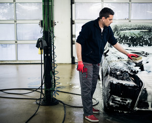 Man worker washing luxury car on a car wash.