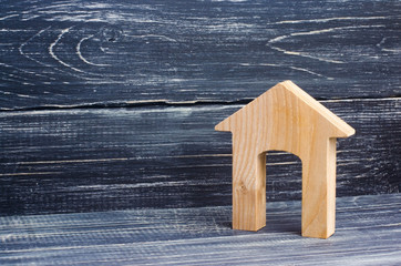 Obraz na płótnie Canvas Figurine of a wooden house with a large doorway on a background of black boards. Concept of real estate, purchase and sale of housing. Affordable housing at a low price. House for the family.