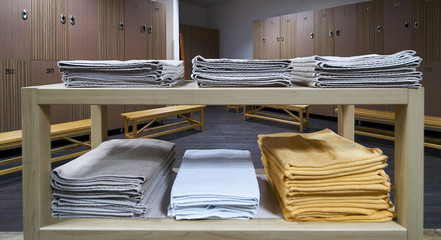 Clean towels shelf in a locker room with wooden benches in luxury fitness gym