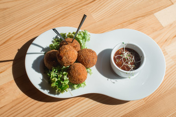 closeup of plate with spanish croquettes served with salad and sauce