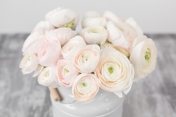 Persian buttercup. Bunch pale pink ranunculus flowers light background. Glass vase on pink vintage wooden table. Wallpaper