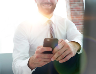 businessman holding a smartphone and looking at the camera
