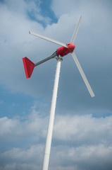 closeup of little wind mill for private electricity production on cloudy sky background