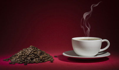 steamed coffee cup and coffee beans on the red background