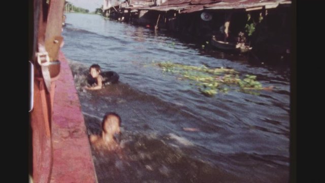 THAILAND, BANGKOK, MAY 1978. Three Shot Sequence Off A Traveling Motorboat, With Inhabitants In Poor Shacks On A Canal And  Children Swimming