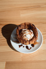 Traditional Mexican dessert churros served with ice cream on white plate on wooden table