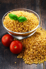 Bowl of uncooked bulgur on wooden table