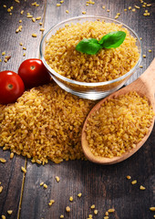 Bowl of uncooked bulgur on wooden table