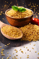 Bowl of uncooked bulgur on wooden table