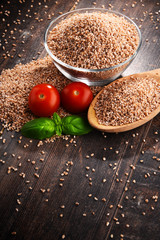 Bowl of uncooked spelt on wooden table