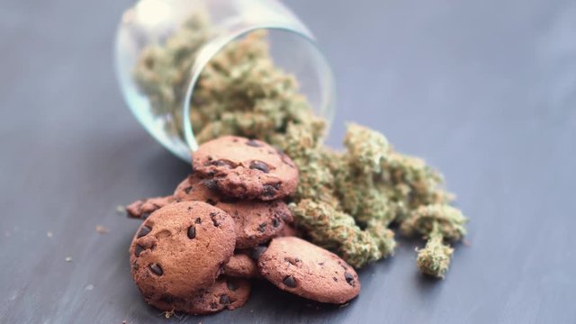 Cookies with cannabis and buds of marijuana on the table. Concept of cooking with cannabis herb. Treatment of medical marijuana for use in food, On a black background top view