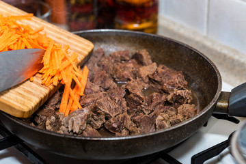Close up adding chopped carrot to beef stew