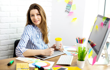 Beautiful young designers discussing ideas and smiling while working in office