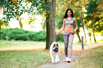 Sports woman walking with dog in the park.
