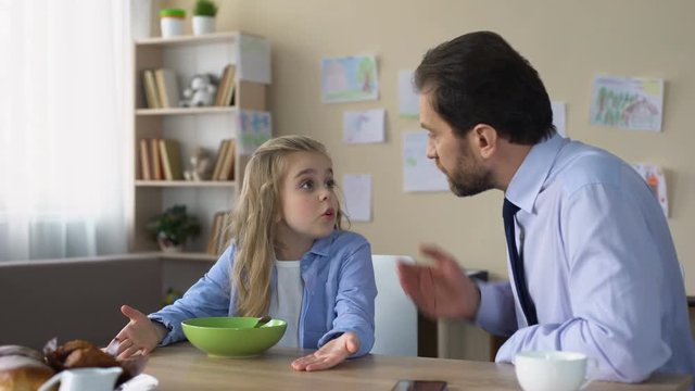 Strict father talking to daughter at kitchen, parent and child conflict, family