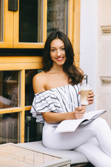 beautiful young girl drinking coffee in the city