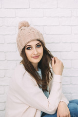woman in knitted hat is sitting near the wall
