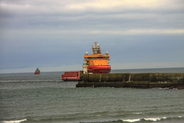 Aberdeen Scotland, UK. Coastline and ship entering harbour. Offshore supply ship.