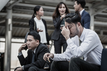 Businesspeople Gossiping Behind Stressed business man.