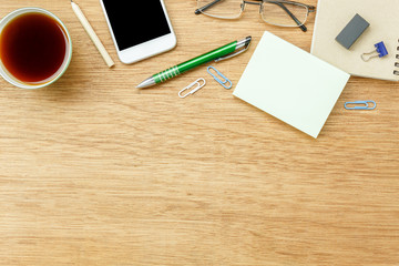 Table top view aerial image stationary on office desk background concept.Flat lay objects the cup of black coffee with essential accessory & mobile phone.Items on modern brown wooden at home studio.
