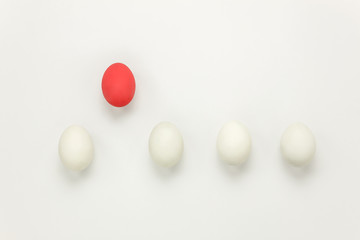 Table top view aerial image of business or Happy Easter holiday background concept.Flat lay red egg outstanding or leader ship other white eggs on modern white paper backdrop.Object different other.
