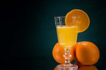 Orangenscheibe am Glas mit Orangensaft und Orangen rechts