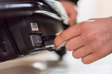Closeup day view teen hand plug in out charging cable into electric scooter