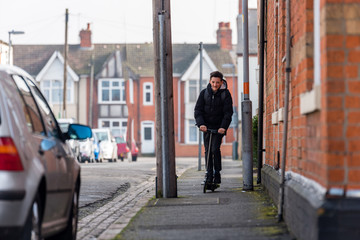 Boy on electrical scooter driving to British school in UK