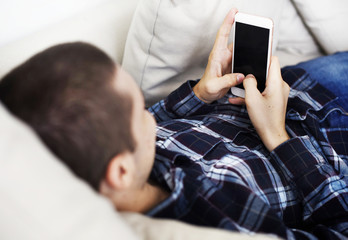 Man laid on the couch using a smarphone