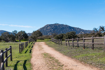 Fototapeta na wymiar A dirt road lined with a wooden fence leading to Mount Woodson at Ramona Grasslands Preserve in San Diego, California.