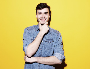 young smiling man standing against yellow background