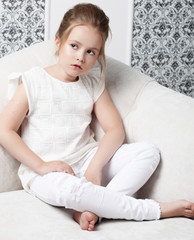 Naklejka premium Girl fashion portrait. Child model sitting in chair.