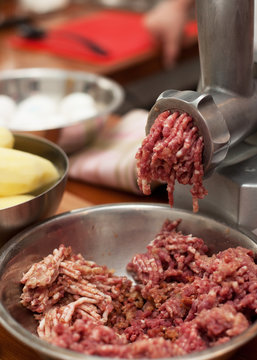 Close up of front part of meat grinder or mincing-machine with mincemeat in.